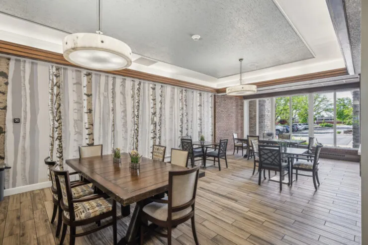 Bright dining room with wood tables, nature-inspired decor, and large windows overlooking, Harvard Square Memory Care